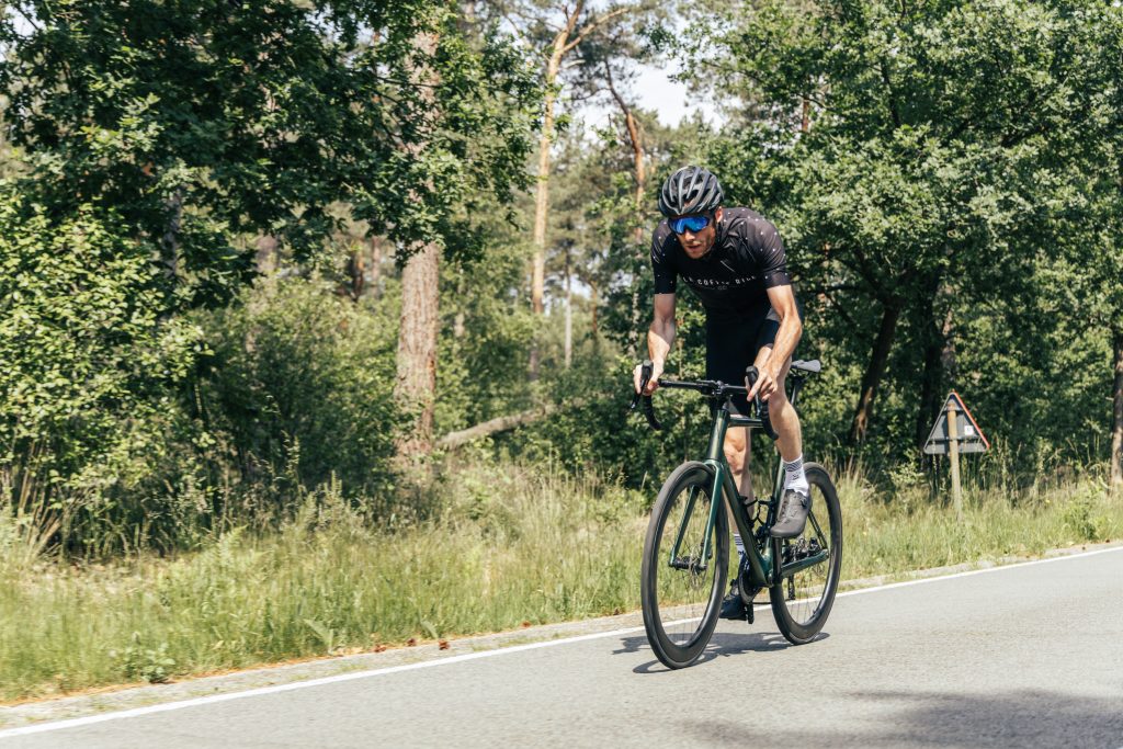 Wielrenner op een Aeross fiets op een zomerse bosweg — het voorjaar is de perfecte tijd om weer buiten te fietsen