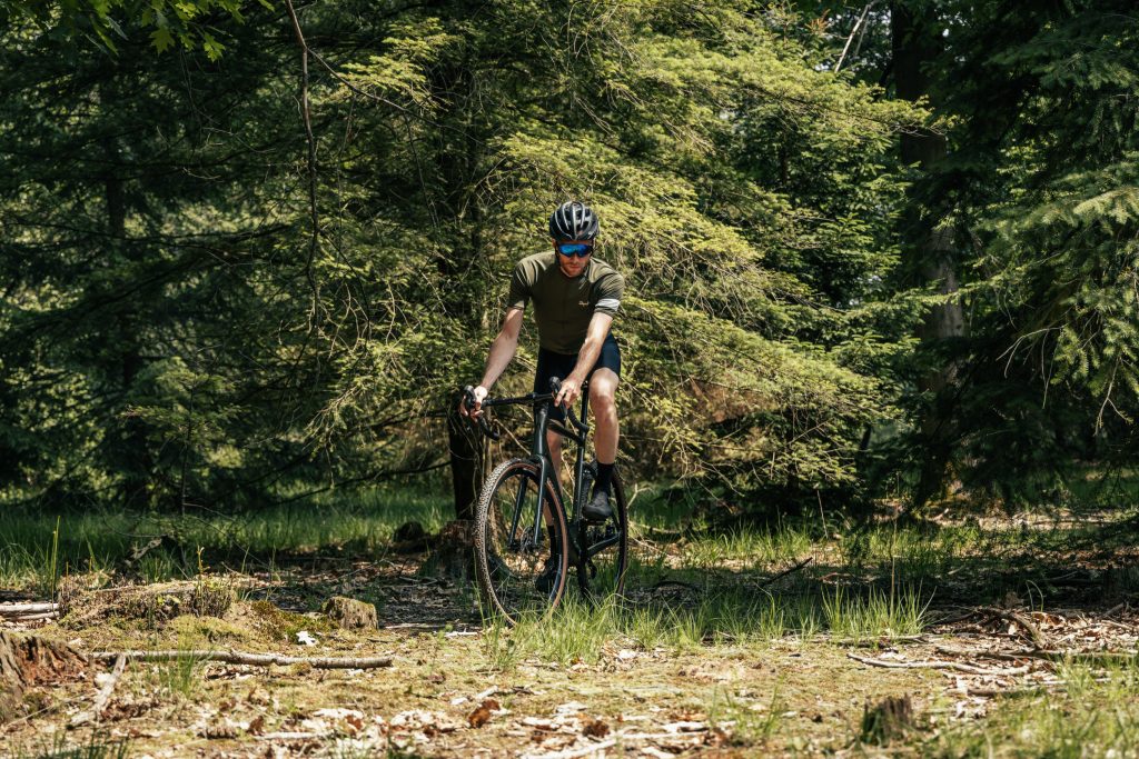 Wielrenner op een Aeross gravelbike off-road door het bos — de keuze voor 1x of 2x hangt af van je rijstijl en terrein