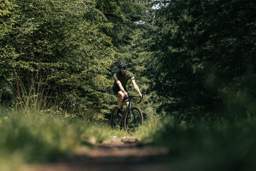 Wielrenner op een Aeross gravelbike op een smal bospad — Nederland heeft prachtige onverharde routes door bossen en natuurgebieden