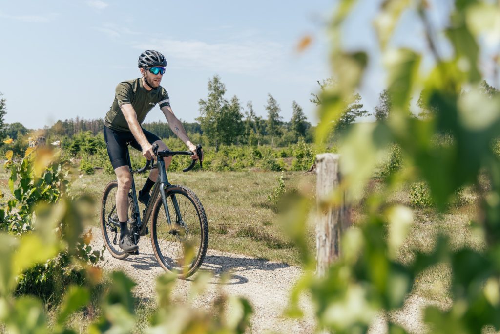 Wielrenner op een Aeross gravelbike op een gravelpad — tubeless banden bieden voordelen op het gebied van comfort en lekpreventie