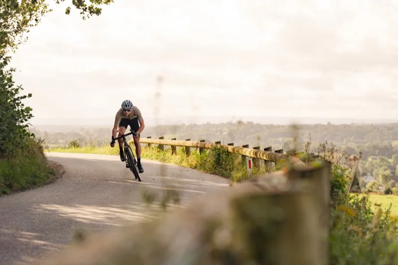 Wielrenner daalt af op een Aeross carbon fiets door het Brabantse heuvellandschap, snelheid en dynamiek van het carbon frame