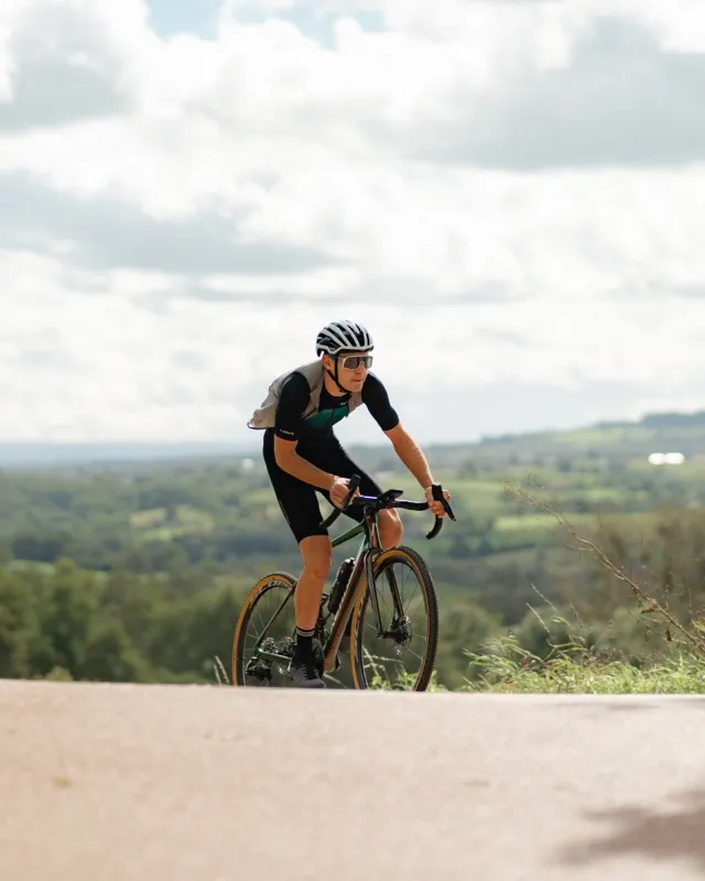 Wielrenner op carbon fiets in heuvellandschap met panoramisch uitzicht