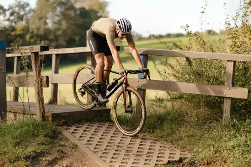 Wielrenner op gravelbike over een brug in natuurlijke omgeving