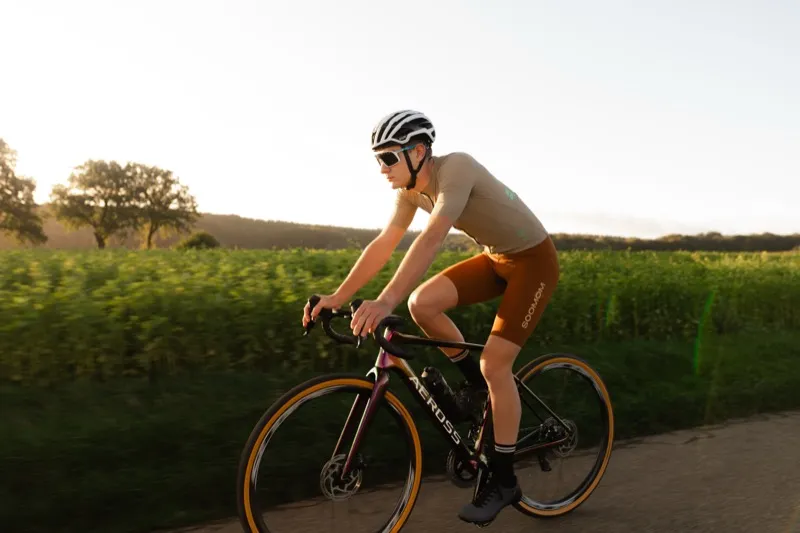 Wielrenner op Aeross fiets in zijprofiel, zitpositie en frame geometrie duidelijk zichtbaar bij golden hour