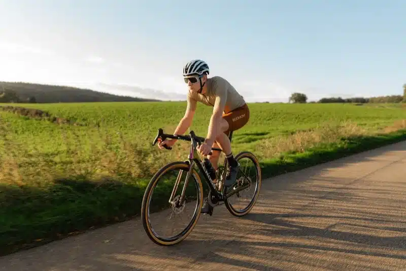 Wielrenner op een Aeross racefiets op een landweg bij zonsondergang